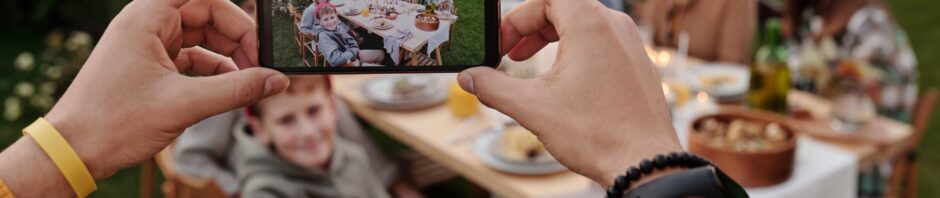 unrecognizable person taking photo of family dinner on smartphone